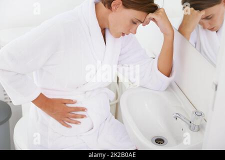 Kampf mit der morgendlichen Krankheit. Eine Schwangerin, die im Badezimmer mit Morgenkrankheit zu kämpfen hat. Stockfoto