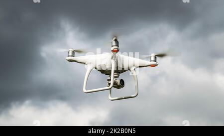 Drohne DJI Phantom 4 im Flug. Dron gegen den bewölkten Himmel. Der Flug der Drohne vor einem Gewitter. Der Flug des Hubschraubers am Himmel. Stockfoto