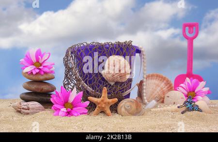 Sandeimer mit Netz und Meeresmuscheln auf Sand mit Himmelshintergrund Stockfoto