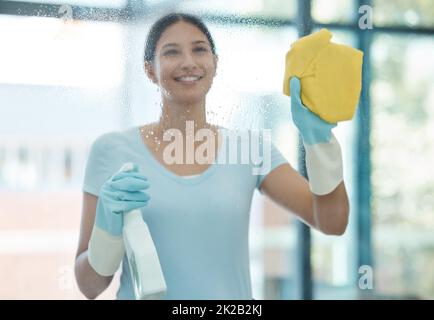 Haus, Fenster und Frau, die ihre Hausfenster mit Glasreinigungsspray putzt. Die Putzfrau, der Angestellte und das Personal lächeln im Frühling Stockfoto