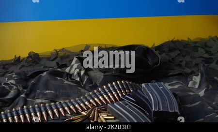 Blau-gelbe Flagge des ukrainischen Nationalsymbols, 5,56mm-Munition, Maschinengewehrkugeln Gürtel, Gewehrmunition in Zeitschriften, ukrainische Uniform und schwarze Militärmütze Stockfoto