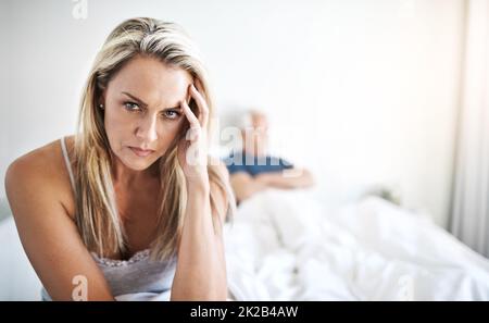 Ich wünschte, all diese Probleme würden einfach verschwinden. Porträt einer reifen Frau, die zu Hause im Hintergrund aufgeregt über ihren Mann schaut. Stockfoto