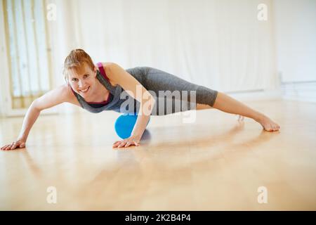 Sich durch Yoga um ihren Körper kümmern. Aufnahme einer Frau, die während eines Yoga-Workouts Walzenschaumübungen macht. Stockfoto