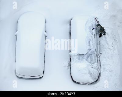 Die Nachwirkungen eines Schneesturms. Hochwinkelige Aufnahme von zwei Autos, die mit Schnee bedeckt sind. Stockfoto