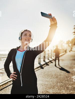 Ich inspiriere andere auch, gesund zu leben. Eine kurze Aufnahme einer sportlichen jungen Frau, die auf der Promenade ein Selfie gemacht hat. Stockfoto