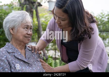 Pflegerin Tochter Hilfe asiatische ältere oder ältere alte Dame Frau auf elektrischen Rollstuhl im Park. Stockfoto