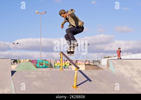 Schleifen wie ein Profi. Aufnahme eines Skateboarders, der einen Trick auf einer Schiene ausführt. Stockfoto