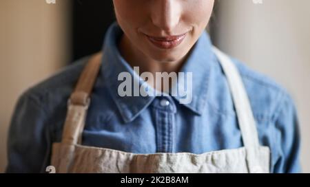 Sie weiß, wie man die beste Tasse Kaffee macht. Eine junge Frau, die eine Schürze trägt. Stockfoto