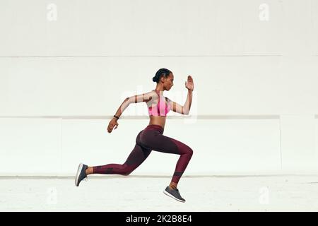 Egal, ob Sie langsam oder schnell gehen, gehen Sie einfach. Aufnahme einer sportlichen jungen Frau beim Laufen. Stockfoto