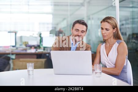 Sie sind ein dynamisches Duo. Aufnahme von zwei Kollegen, die im Büro zusammen einen Laptop benutzen. Stockfoto