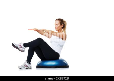 Hart arbeiten, um ihre Fitness zu verbessern. Eine junge Frau, die beim Training auf einem bosu-Ball sitzt. Stockfoto