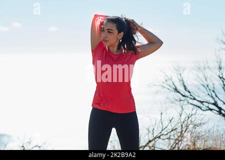 Vorbereitung auf einen Lauf. Kurzer Schuss einer attraktiven jungen Frau, die sich vor dem Training aufwärmt. Stockfoto