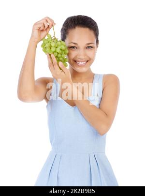 Frisch und saftig. Junge Frau lächelt, während sie ein Traubenbündel hochhält - isoliert auf Weiß. Stockfoto