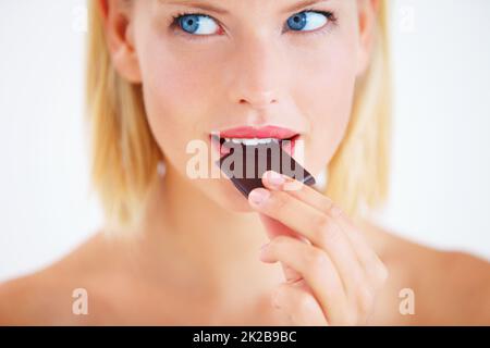 Nur einen kleinen Block entfernt. Junge Frau genießt ein köstliches Stück Schokolade. Stockfoto