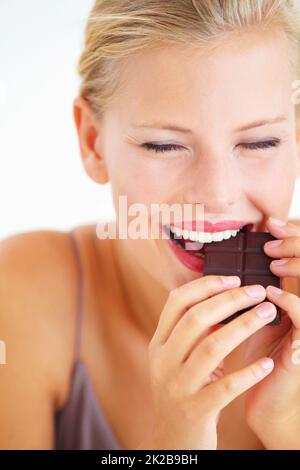 Ah, das ist erstaunlich. Junge Frau genießt ein köstliches Stück Schokolade mit Freude. Stockfoto