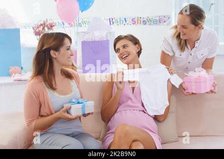 Ihr verdirbt mich - und das Baby. Eine junge, schwanger Frau erhält Geschenke von ihren hübschen Freunden an ihrer Babydusche. Stockfoto