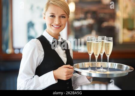 Funkeln Sie mit einem erfrischenden Glas edlen Champagners. Die freundliche Kellnerin hielt bei einer Feier ein Tablett mit Sektgläsern in den Händen. Stockfoto