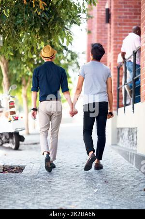 Liebe hat keine Einschränkungen. Aufnahme eines jungen schwulen Paares, das im Freien spazierengeht und dabei die Hände hält. Stockfoto