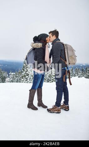 Unsere Liebe ist ein großes Abenteuer. Aufnahme eines Küssens eines Paares, das den Tag im Schnee verbringt. Stockfoto