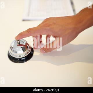 Klingelt in seinem Urlaub. Eine Hand klingelte an einem Check-in-Schalter des Hotels. Stockfoto