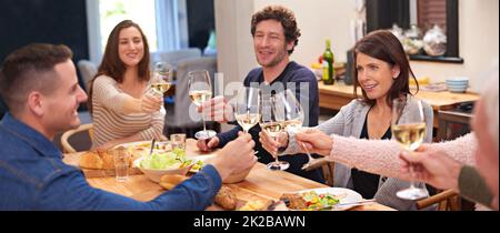 Heres to family. Eine kurze Aufnahme einer Familie, die am Esstisch ein Essen teilt. Stockfoto