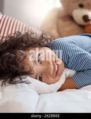 Sehen Sie die Welt so, wie er es tut. Porträt eines entzückenden Jungen, der sich zu Hause auf seinem Bett entspannt. Stockfoto