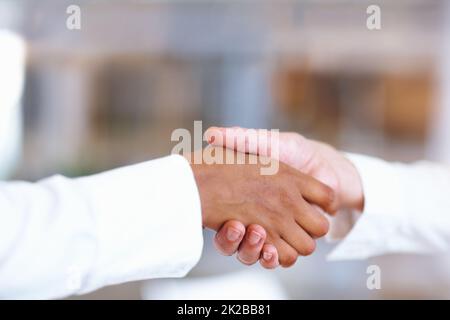 Fester Händedruck. Nahaufnahme eines multirassischen Handshakes zwischen zwei Geschäftsleuten. Stockfoto