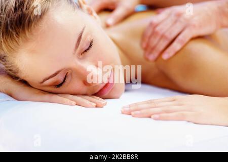 Junge Dame genießt eine Körpermassage in einem Spa. Hübsches junges Mädchen, das eine Körpermassage in einem Spa genießt. Stockfoto