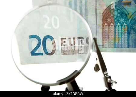 Jeder Euro wird überprüft. Aufnahme einer 20-Euro-Rechnung unter einer Lupe. Stockfoto