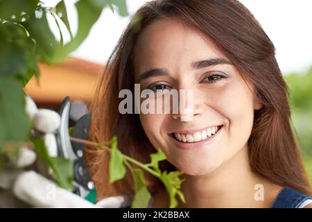 Shes leidenschaftlich über Gartenarbeit. Nahaufnahme Porträt einer attraktiven jungen Frau, die in ihrem Garten arbeitet. Stockfoto