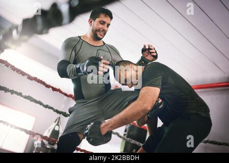 Was für ein Schuss aus dem nichts. Aufnahme von zwei jungen männlichen Boxern, die sich während eines Trainingspartnerspiels in einem Boxring im Fitnessstudio gegenüberstehen. Stockfoto