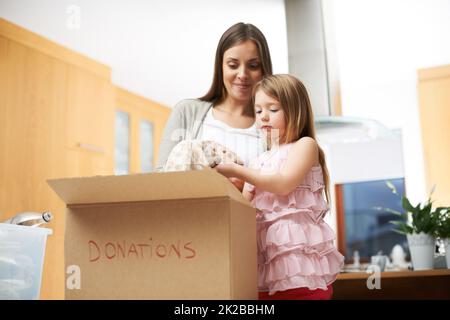 Mummys kleiner Helfer. Ein junges Mädchen hilft ihrer Mutter bei karitativen Arbeiten. Stockfoto