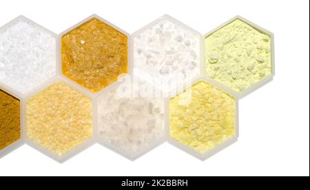 Chemischer Inhaltsstoff in hexagonalem molekularförmigem Behälter. Mikrokristallines Wachs, Carnaubawachs, Cetyl-Esterwachs, Schwefelpulver, Curcuma-Pulver, Candelilla Wax, Flake Salz und Natriumsulfid Flocken. Stockfoto