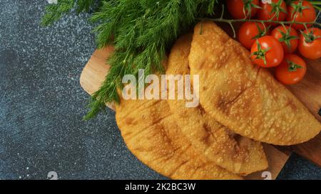 Cheburek mit Fleisch und Kirschtomaten. Traditionelle rumänische, ukrainische, russische und tatarische Küche Nationale Ostmahlzeit. Fleischpastete mit Rind, Kalb oder Lamm Stockfoto