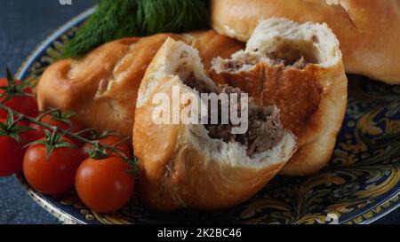 Ukrainische Patties (Pasties, Hot Cakes, Piroschki, Pies) auf einem Teller. Traditionelle hausgemachte Backpasteten mit Fleisch Stockfoto