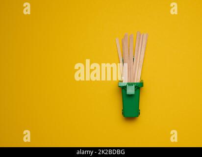 Einweg-Holzstäbchen zum Rühren von heißen Getränken auf gelbem Hintergrund. Kaffee- und Teelöffel Stockfoto
