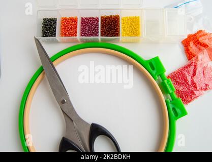 Flach liegendes Zubehör für Nadel und Stickerei, Scheren und Perlen auf weißem Hintergrund Stockfoto