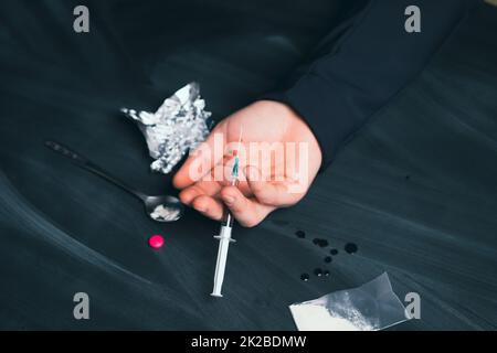 Drogenabhängiger mit Spritzen unter Drogeneinfluss. Stockfoto