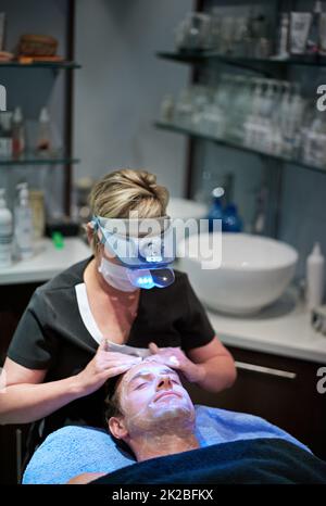 Jugendliche Haut kommt bald. Ein Mann bekommt eine Gesichtsbehandlung in einer Schönheitsklinik. Stockfoto