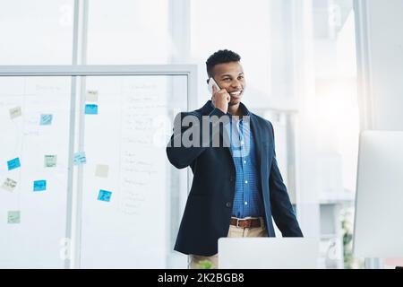 HES immer verfügbar, wenn seine Kunden ihn brauchen. Aufnahme eines jungen Geschäftsmannes, der in einem Büro auf einem Mobiltelefon spricht. Stockfoto