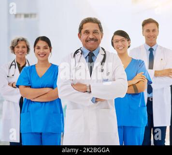 Ihre Gesundheit ist unsere oberste Priorität. Porträt eines medizinischen Teams, das mit gefalteten Armen in einem Krankenhaus steht. Stockfoto