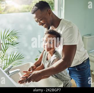 Persönliche Hygiene hält Sie sauber und beugt Krankheiten vor. Aufnahme eines Vaters, der seinem Sohn dabei hilft, sich die Hände am Wasserhahn im Badezimmer zu Hause zu waschen. Stockfoto