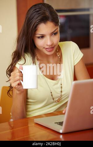 Praktische Heimtechnologie. Eine junge Frau, die ihren Laptop in der Küche benutzt. Stockfoto