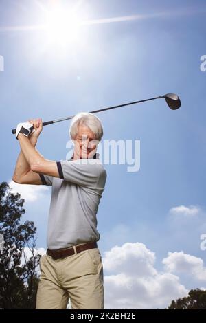 HES perfektionierte seinen Schwung über die Jahre. Senior Mann in vollem Gange während einer Runde Golf gegen einen blauen Himmel. Stockfoto