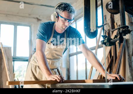 Tischler auf dem Band sah in seiner Holzwerkstatt Stockfoto