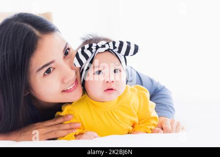 Mutter spielt und lächelt zusammen mit seinem neugeborenen kleinen Baby Stockfoto