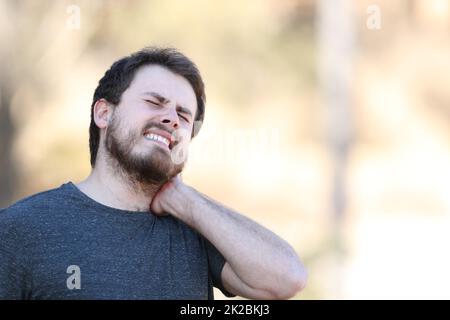 Gestresster Mann mit Nackenschmerzen in der Natur Stockfoto