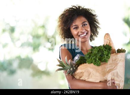 Beutel voller Gesundheit. Junges Mädchen lächelt, während sie ihre Lebensmittel hält - isoliert. Stockfoto