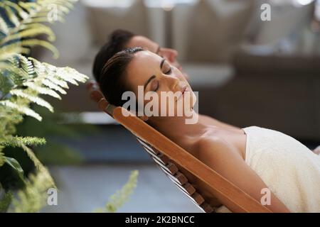 Ruhe und Frieden in Luxus. Eine kurze Aufnahme eines reiferen Paares, das sich Seite an Seite auf Liegestühlen draußen entspannt. Stockfoto