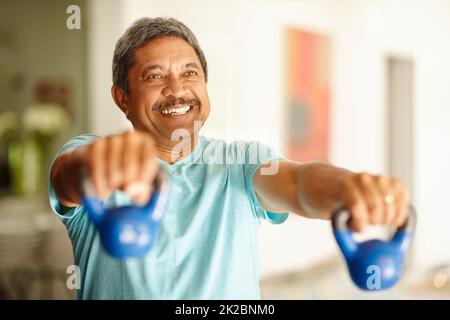 Stark bleiben und sich großartig fühlen. Kurzer Schuss eines reifen Mannes, der Hanteln hebt. Stockfoto